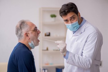 Yaşlı erkek hasta genç doktor otorhinolaryngologis 'i ziyaret ediyor.