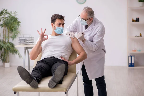 Junge männliche Patientin besucht alten Arzt im Impfpass — Stockfoto