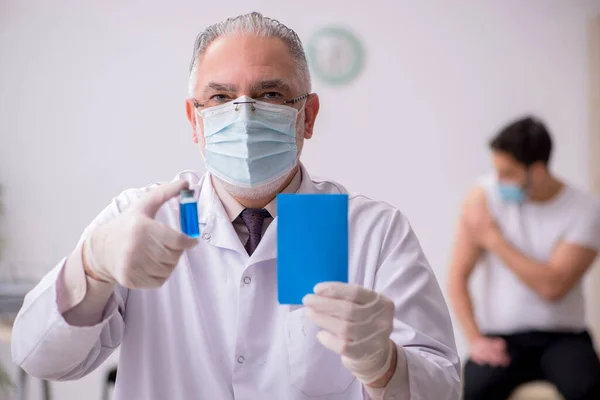 Jeune patient de sexe masculin visitant un vieux médecin en conce de vaccination — Photo