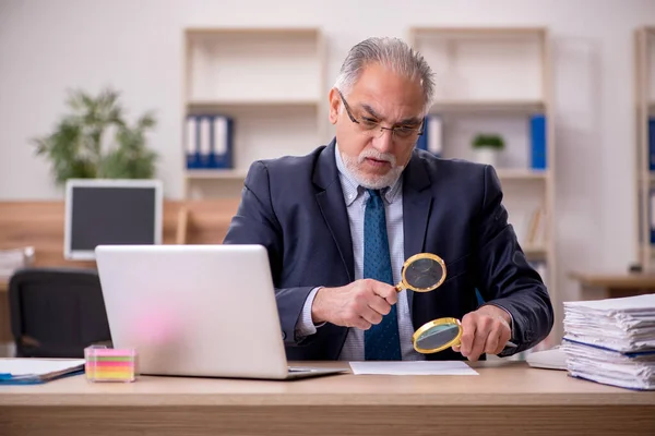 Viejo auditor empleado sosteniendo loupe en el lugar de trabajo —  Fotos de Stock