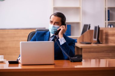 Ofiste maske takan genç bir erkek çalışan.