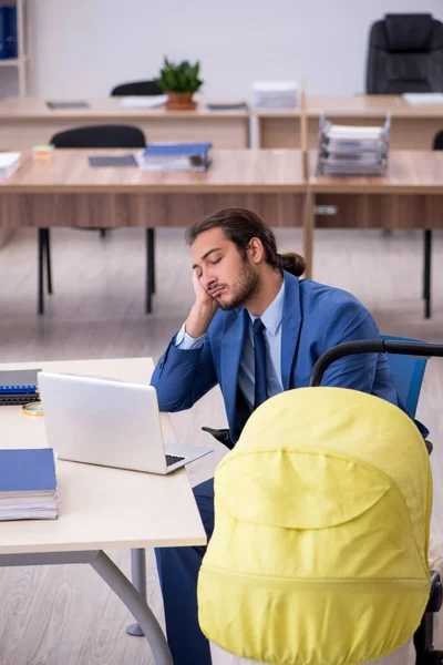 Young male employee looking after new born at workplace — Stock Photo, Image