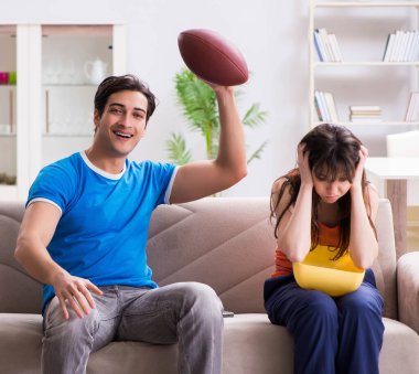 Adam karısıyla Amerikan futbolu seyrediyor.