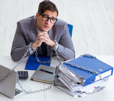 Ofis masasına zincirlenmiş meşgul bir çalışan.