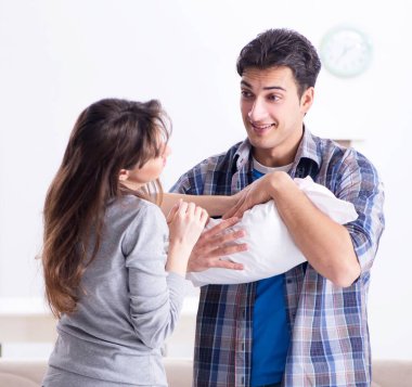 Yatağın yanında yeni doğmuş bebekleri olan genç ebeveynler.