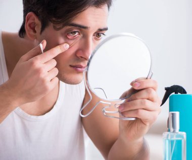 Genç yakışıklı adam aynaya bakıyor.