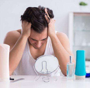 Genç yakışıklı adam aynaya bakıyor.