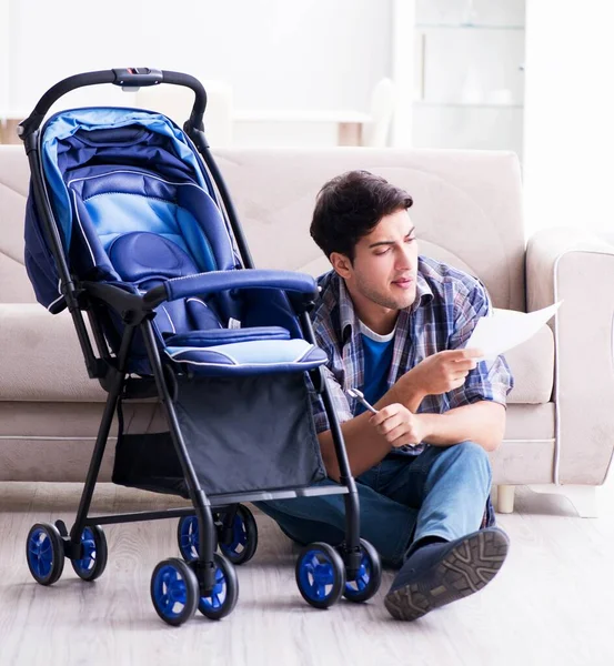 Jovem pai montando carrinho de bebê em casa — Fotografia de Stock