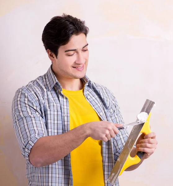 Hombre joven aplicando yeso en la pared en casa — Foto de Stock