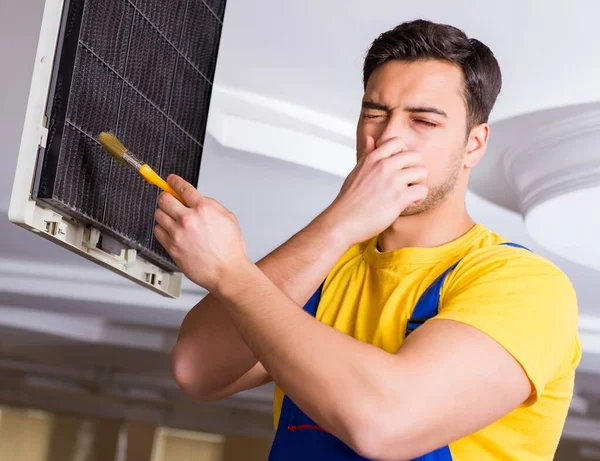 Repairman repairing ceiling air conditioning unit