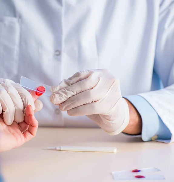 Doctor taking blood samples from finger — Stock Photo, Image