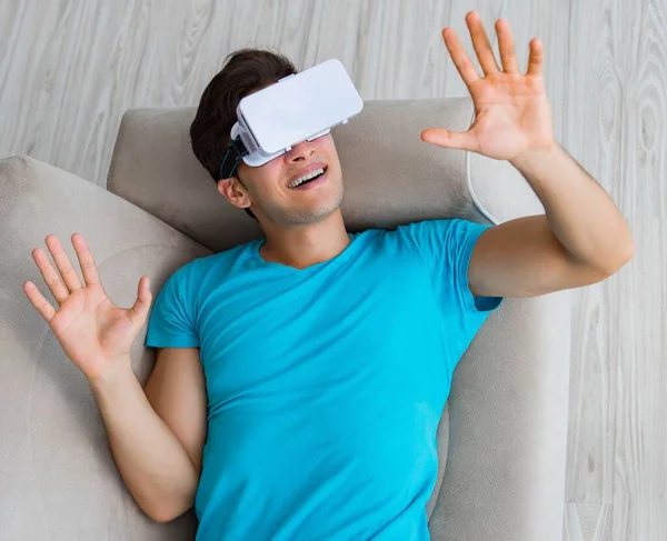 Mladý muž nosí VR brýle relaxační na pohovce — Stock fotografie