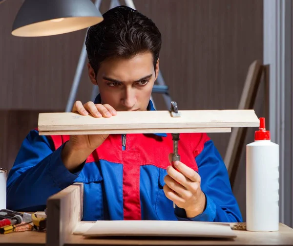 Giovane uomo incollaggio pezzi di legno insieme nel concetto fai da te — Foto Stock