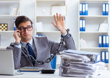 Ofis masasına zincirlenmiş meşgul bir çalışan.