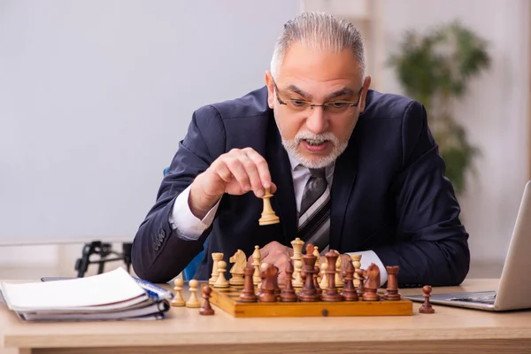 Viejo empleado jugando ajedrez en el lugar de trabajo — Foto de Stock