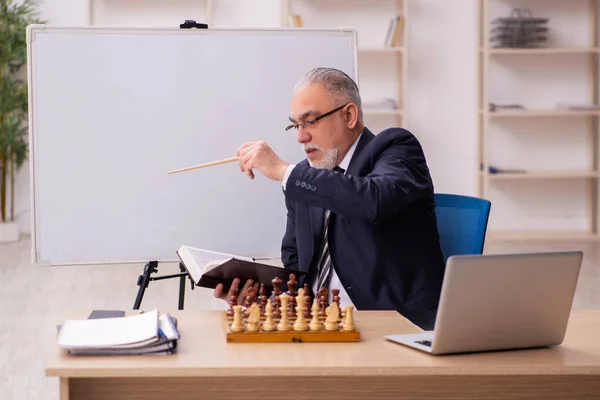 Viejo empleado jugando ajedrez en el lugar de trabajo — Foto de Stock