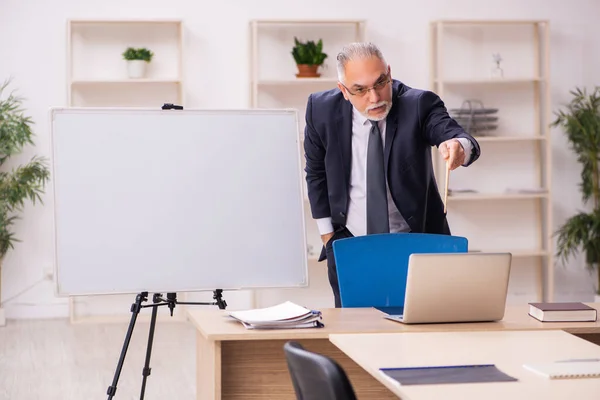 Παλιό αρσενικό εργοδότη μπροστά από λευκό πίνακα — Φωτογραφία Αρχείου