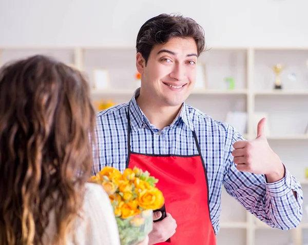 Asistente de floristería vendiendo flores a cliente femenino — Foto de Stock