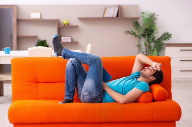 Genç erkek öğrenci turuncu koltukta oturuyor.