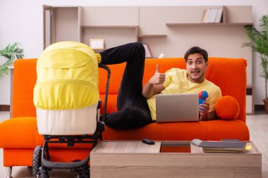 Genç adam evde yeni doğan çocuğa bakıyor.