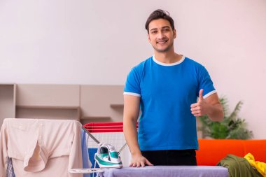 Genç adam evde ütü yapıyor.