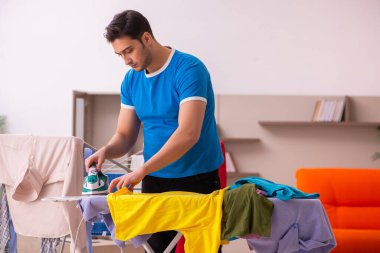 Genç adam evde ütü yapıyor.