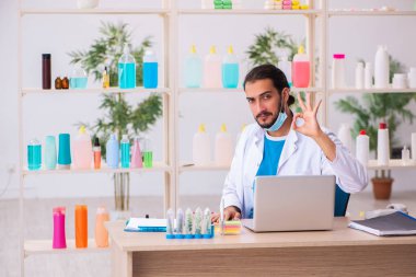 Genç erkek kimyager laboratuarda sabun test ediyor.