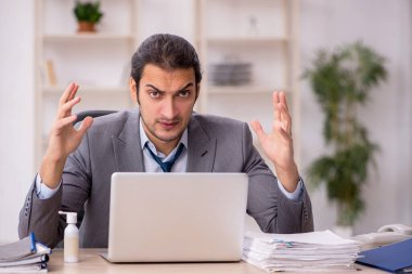 Ofisteki aşırı işten memnun olmayan genç bir erkek işçi.