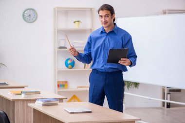 Beyaz tahtanın önünde genç bir erkek öğretmen.