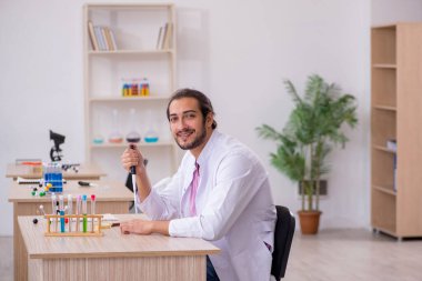 Sınıftaki masada oturan genç bir kimyager.