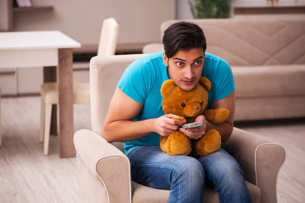 Young man sitting with bear toy at home