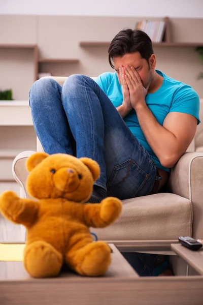 Junger Mann sitzt mit Bärenspielzeug zu Hause — Stockfoto