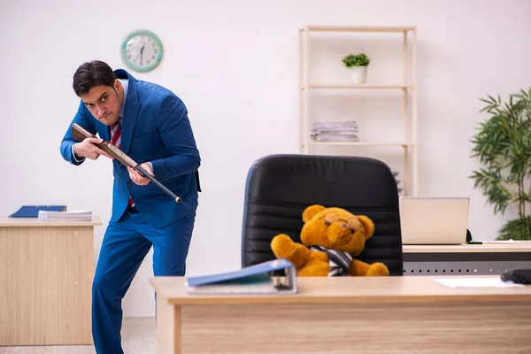 Jovem funcionário masculino e seu chefe urso de brinquedo em conceito engraçado — Fotografia de Stock