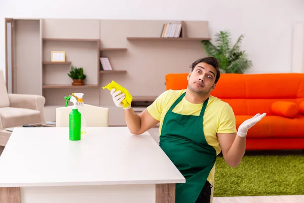 Jovem empreiteiro limpando a casa dentro de casa — Fotografia de Stock