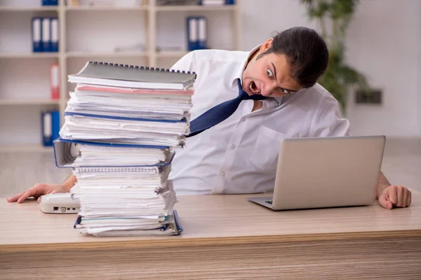 Jeune employé masculin et beaucoup de travail au bureau — Photo