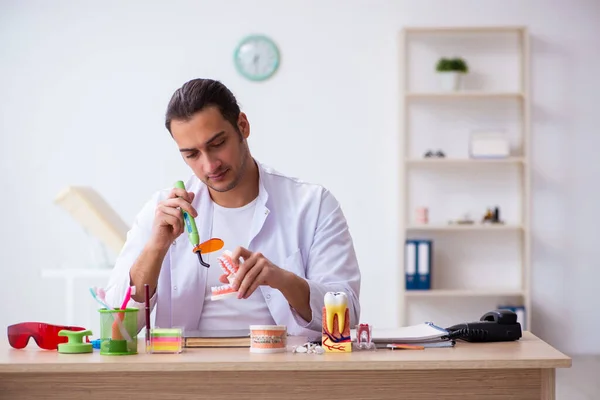 Jonge mannelijke tandarts werkzaam in de kliniek — Stockfoto