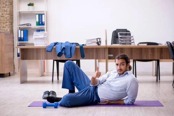 Young male employee doing sport exercises during break — Stock Photo, Image