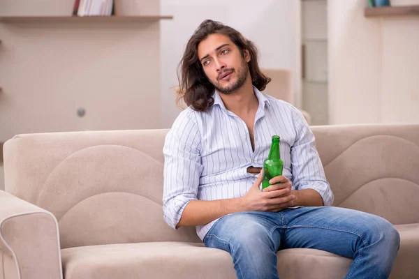 Młody człowiek pijący alkohol w domu — Zdjęcie stockowe