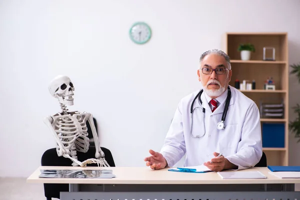 Velho médico masculino e paciente esqueleto na clínica — Fotografia de Stock