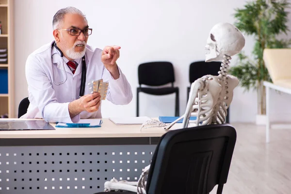 Alte männliche Arzt und Skelett-Patient in der Klinik — Stockfoto