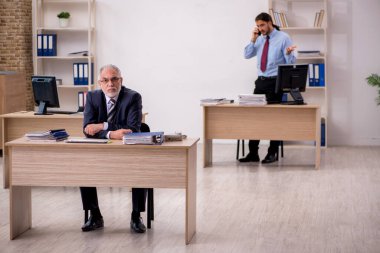 Yaşlı bir patron ve ofiste çalışan genç bir çalışan.