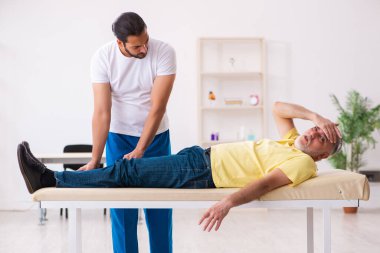 Yaşlı erkek hasta, genç erkek doktor masörünü ziyaret ediyor.