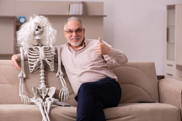 Old man sitting on the sofa with the female skeleton — Stock Photo, Image