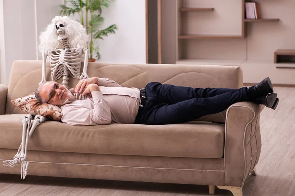 Alter Mann sitzt auf dem Sofa mit dem weiblichen Skelett — Stockfoto