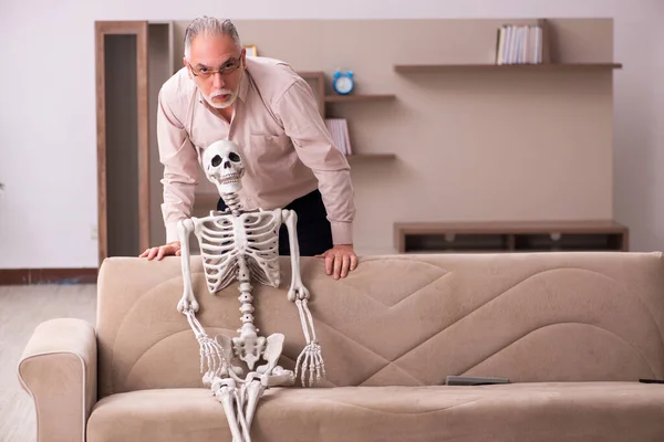 Oude man zittend op de bank met het vrouwelijke skelet — Stockfoto