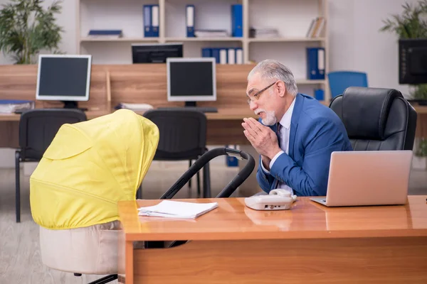 Empleado de negocios envejecido que cuida al recién nacido en el lugar de trabajo — Foto de Stock