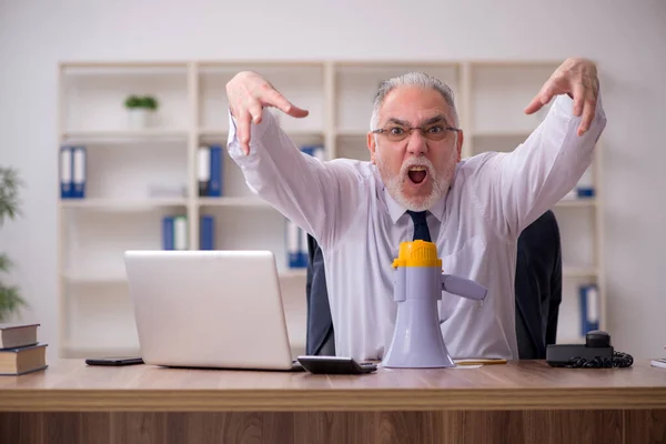 Viejo empleado sosteniendo megáfono en el lugar de trabajo —  Fotos de Stock