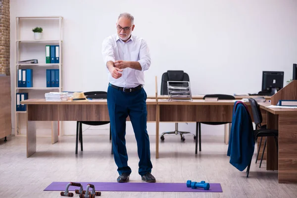 Old businessman employee doing sport exercises in the office — Stock Photo, Image