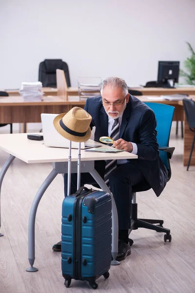 Old male employee preparing for travel in the office — Stock Photo, Image