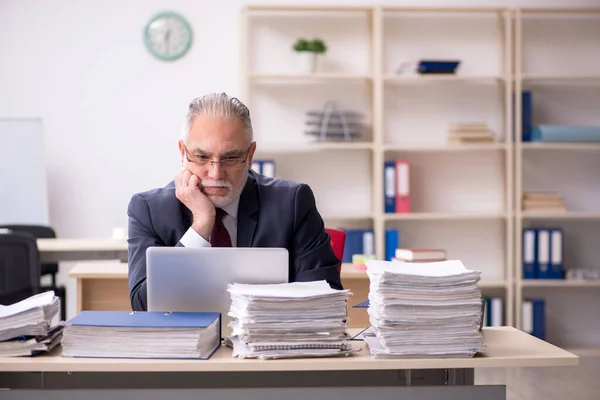 Überalterte männliche Mitarbeiter und zu viel Arbeit am Arbeitsplatz — Stockfoto